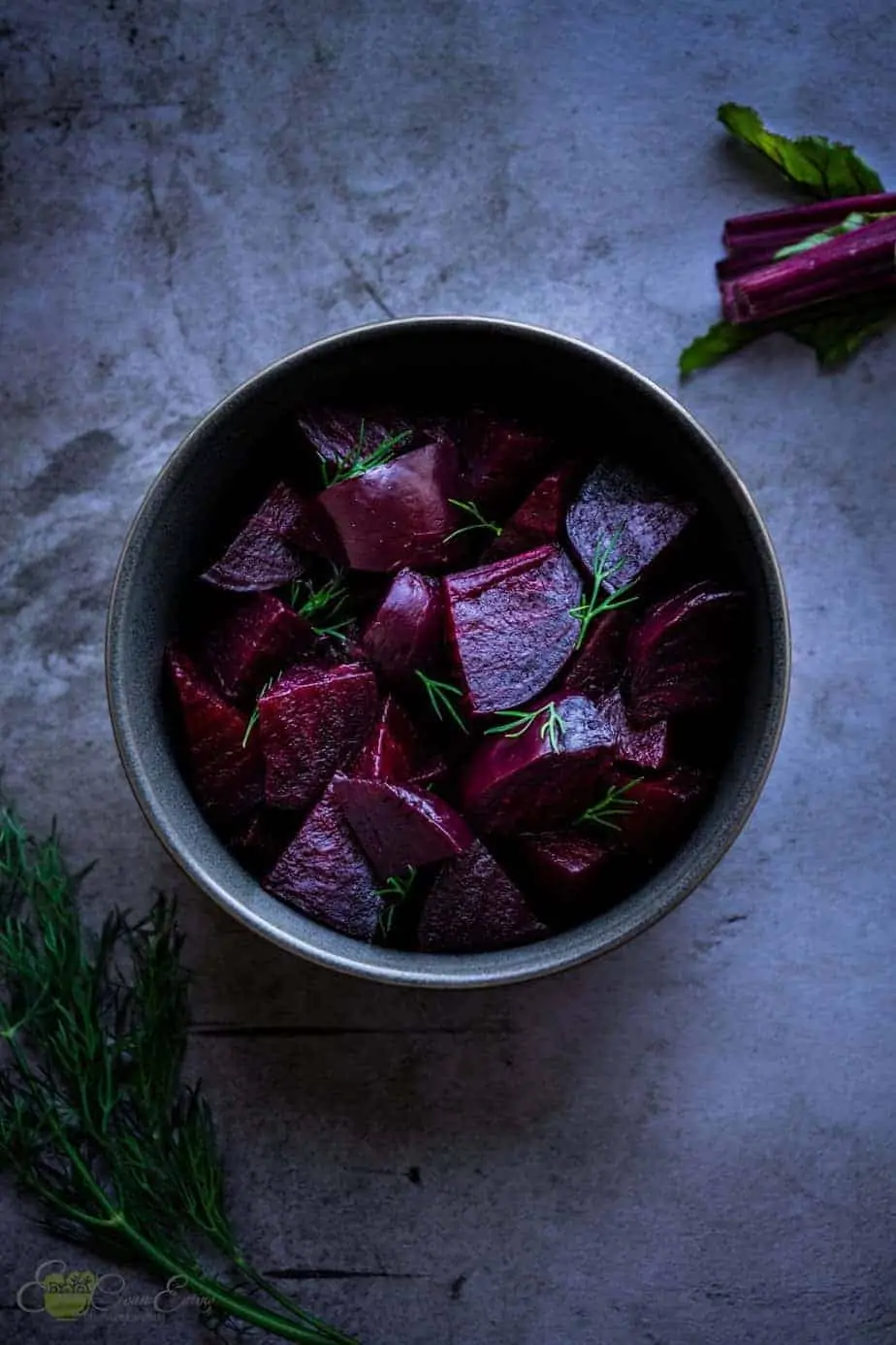 fully cooked beets in a bowl with some dill for garnish.