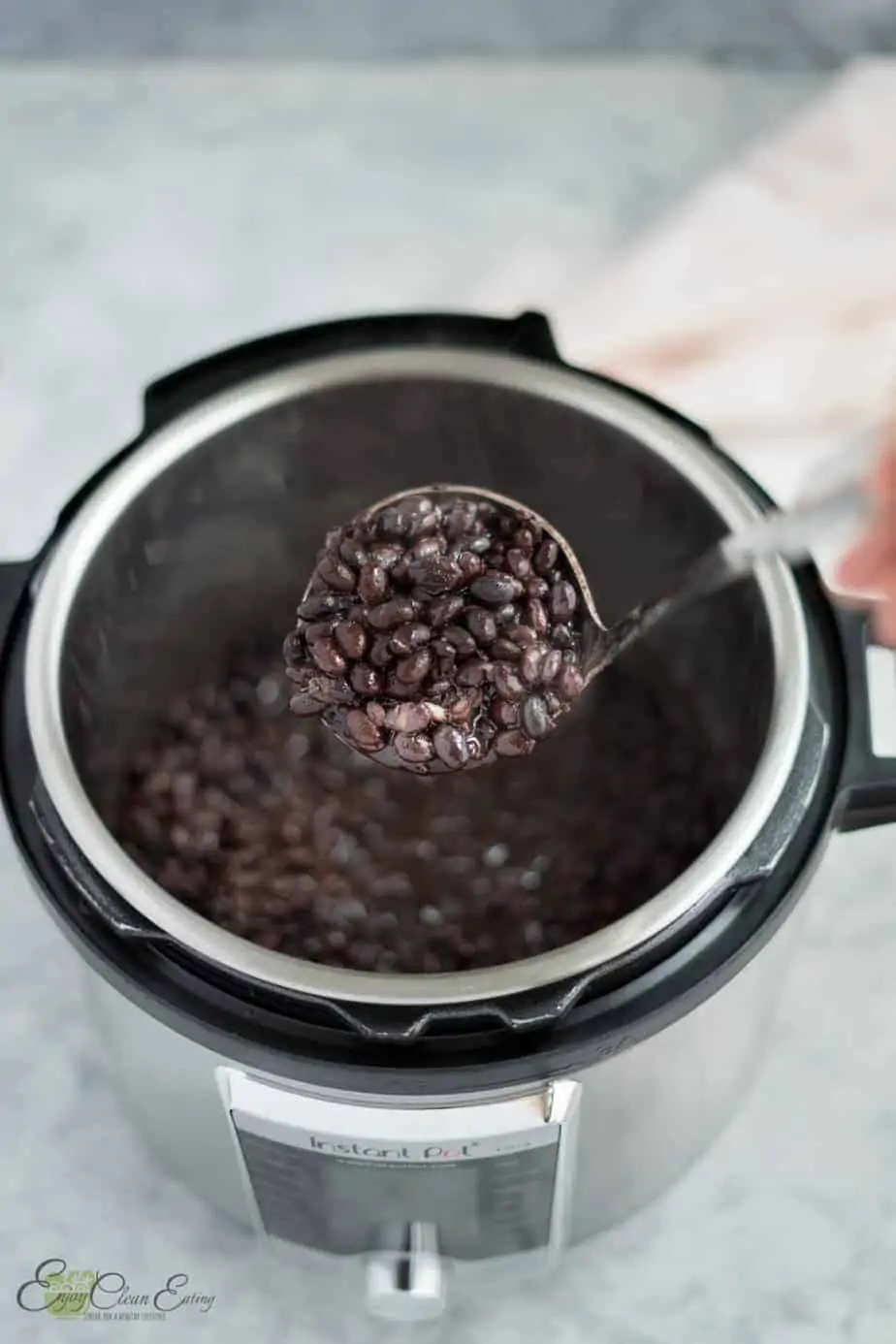 holding a soup serving spoon full of the fresh instant pot black beans