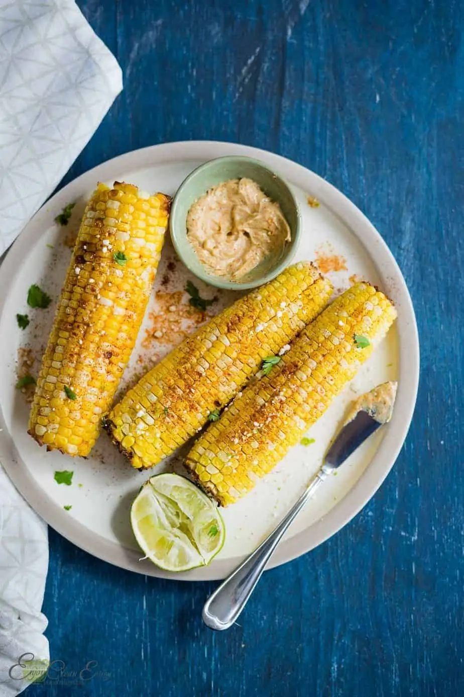 air fryer corn on the cob recipe. corns sprinkle with paprika, goat cheese and cilantro. serve with a chili lime butter and lime wedges.