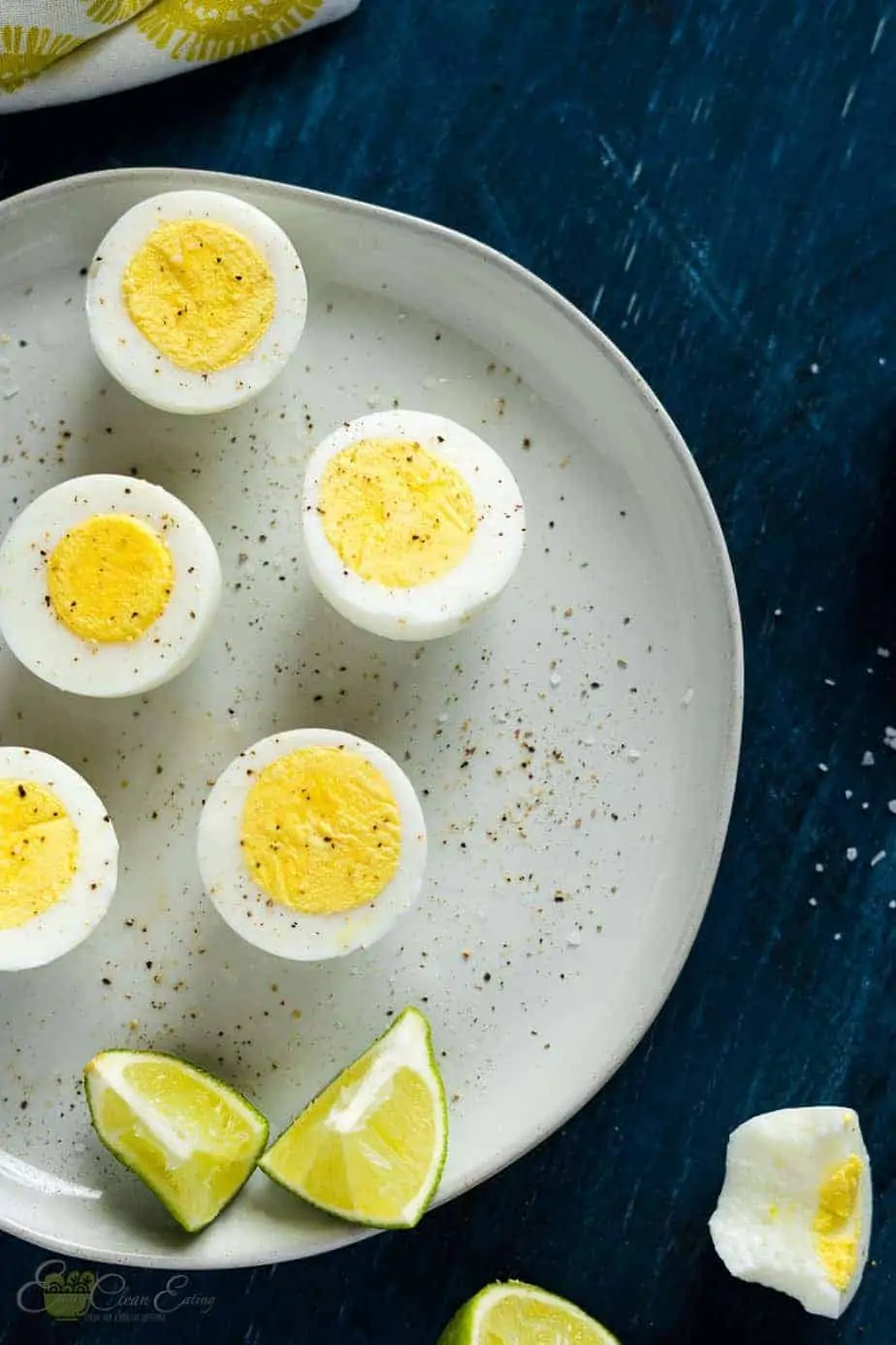 Perfectly cooked air fryer hard boiled eggs sprinkle with salt and peppercorn serve in a plate with lime wedges.