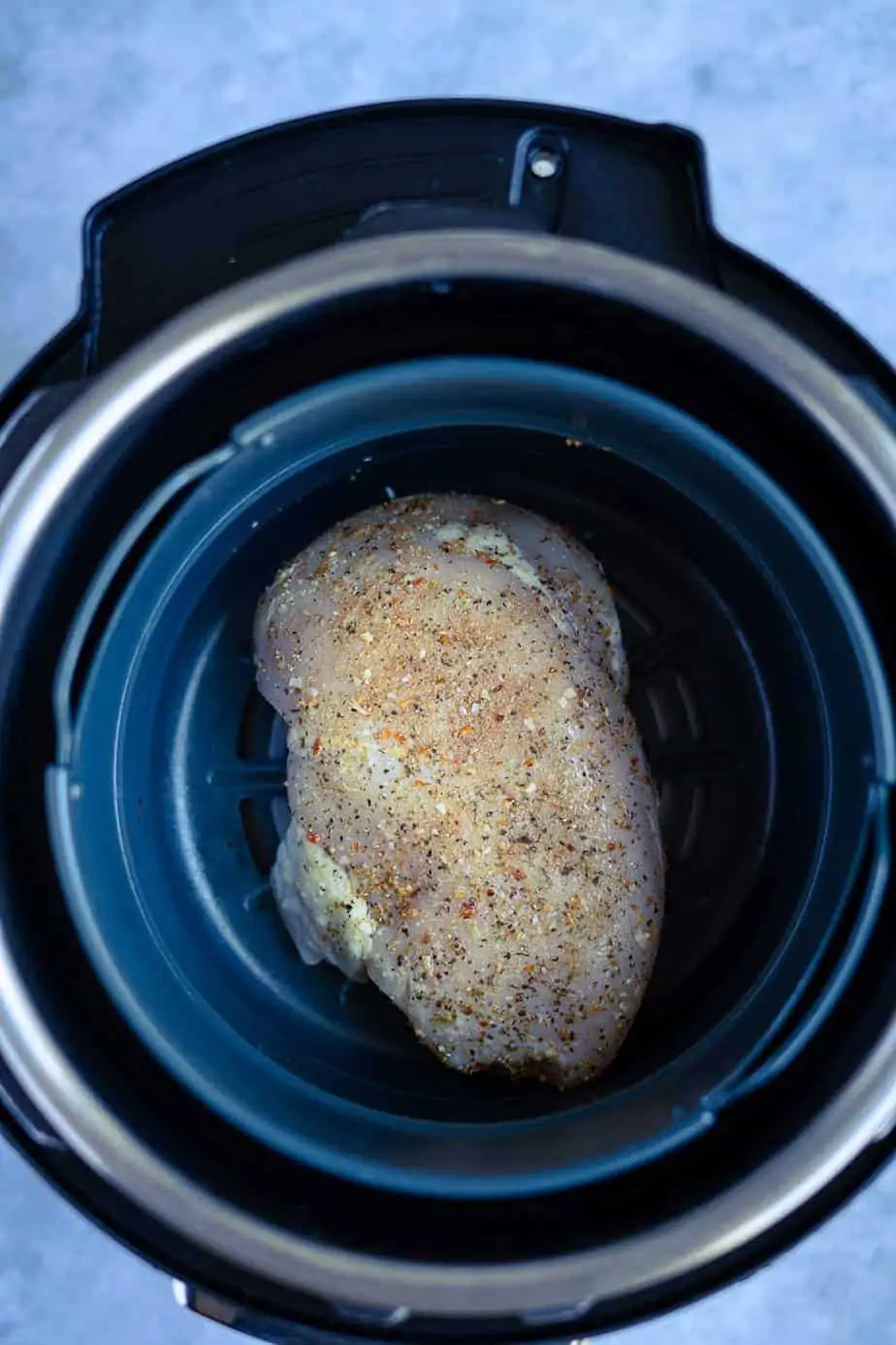 cooking frozen chicken breast in the air fryer with a salt free seasoning and salt to taste inside the air fryer basket.