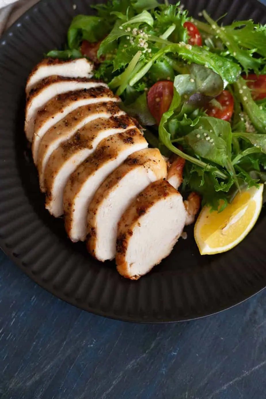 perfectly cooked frozen chicken breast sliced and served with a salad of baby lettuces mix and cherry tomatoes.