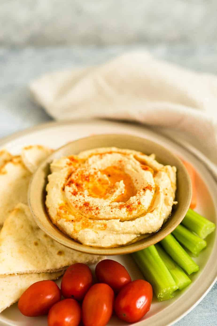 a bowl with hummus drizzle with olive oil and sprinkle with smoked paprika. serve with veggies and pita bread