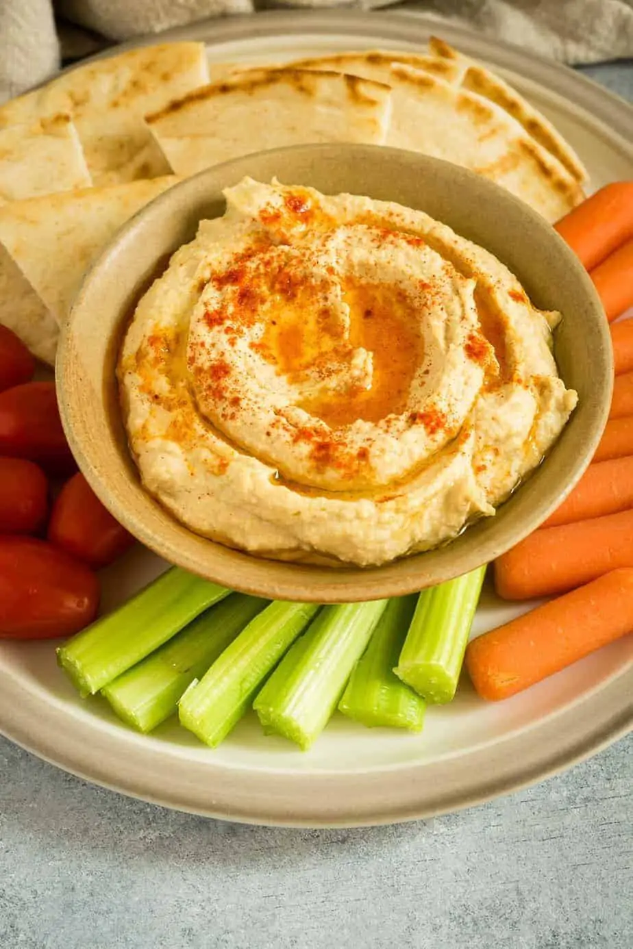 instant pot hummus serve with pitta bread, carrots, celery and cherry tomatoes.