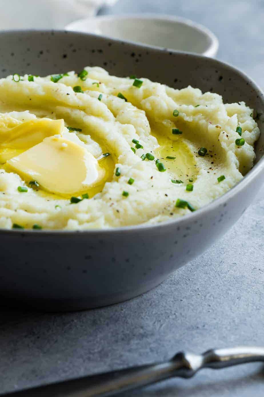 instant pot mashed cauliflower serve in a bowl with extra butter and chives.