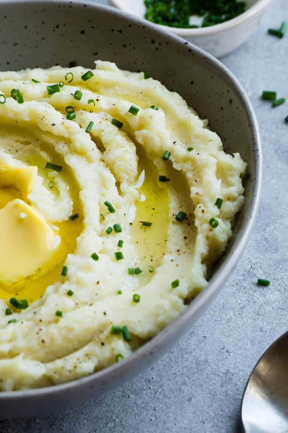 a close up of the creamy mashed cauliflower with melted butter and chives.
