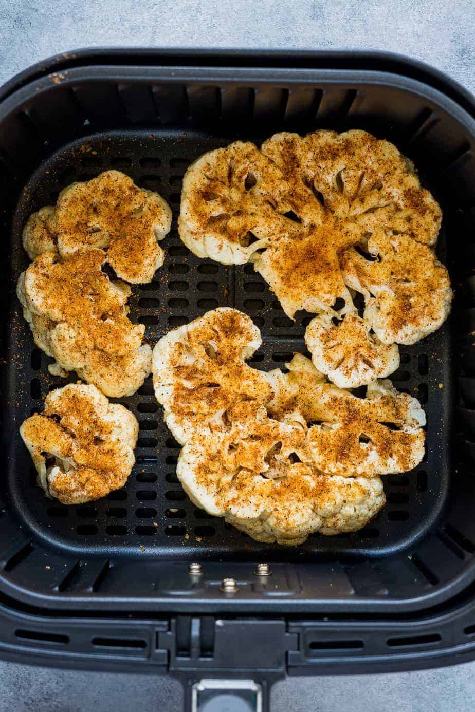 Season cauliflower steaks inside the air fryer basket
