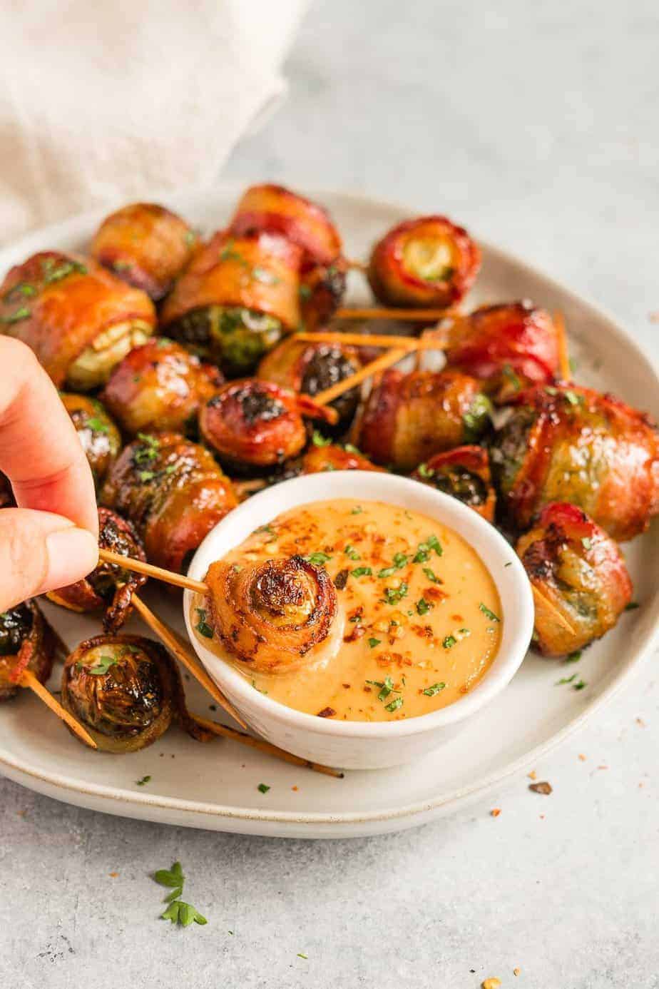 Dipping one bacon wrapped Brussels sprout in the tahini sauce.