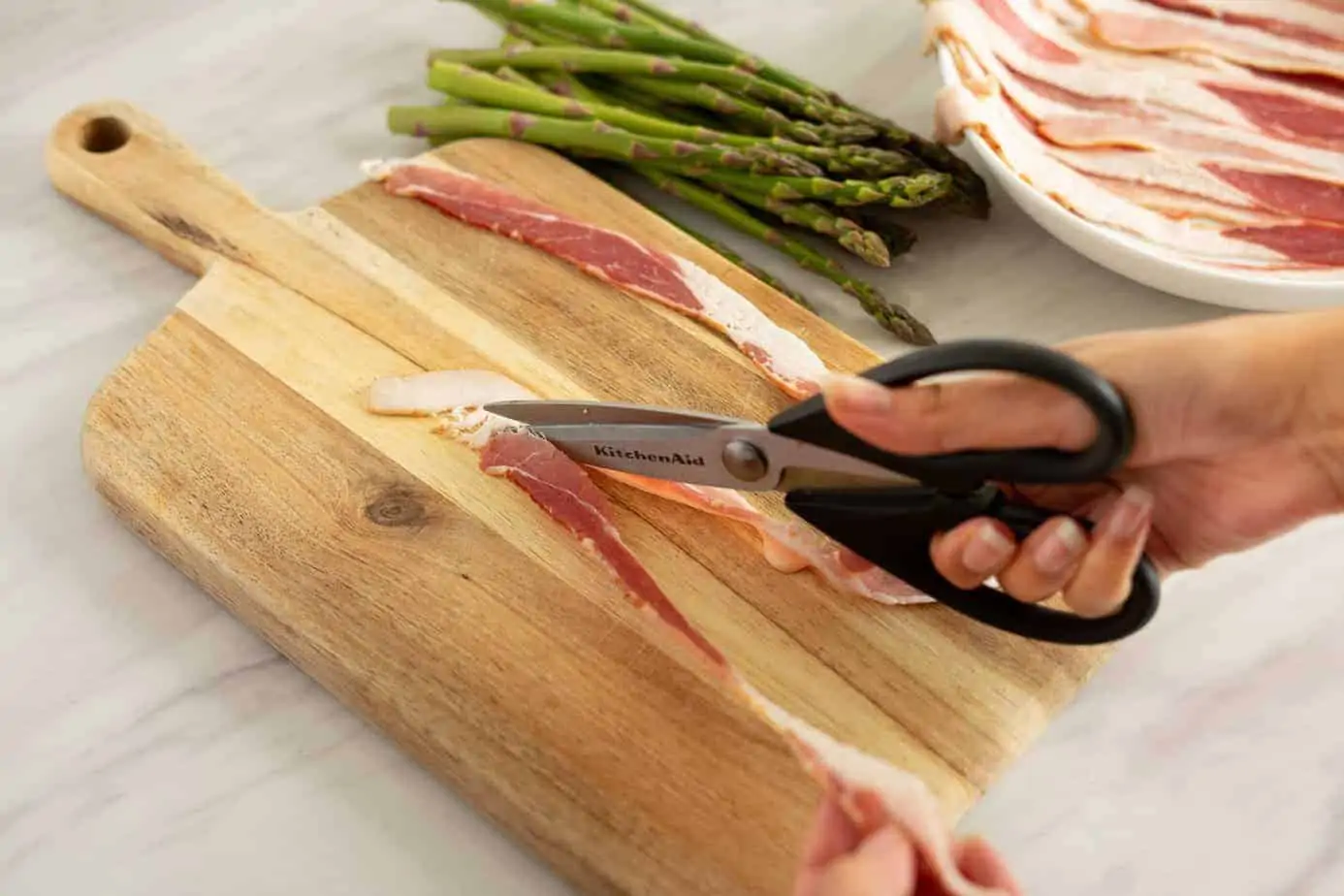 cutting the bacon slices with kitchen shears.