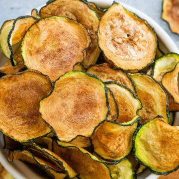 Crispy air fryer zucchini chips in a bowl.
