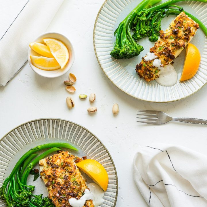 Air fryer halibut with pistachios crust serve with broccolini and lemon wedges.