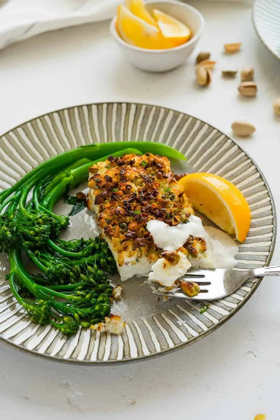 Perfectly cooked fish serve with a side of broccolini and lemon wedges.