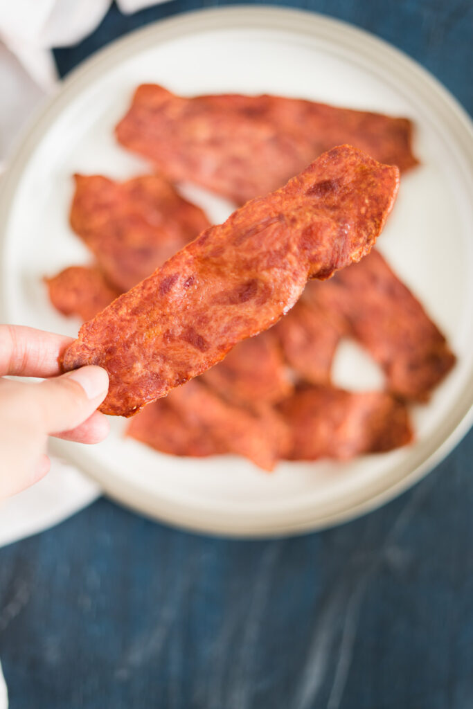 holding a large pieces of turkey bacon after air frying until reach a level of crispiness.