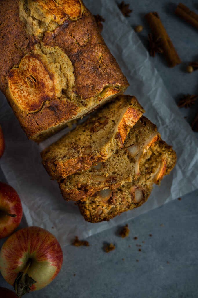 Freshly bake apple bread with slices of apple on top and some fall spices on the background