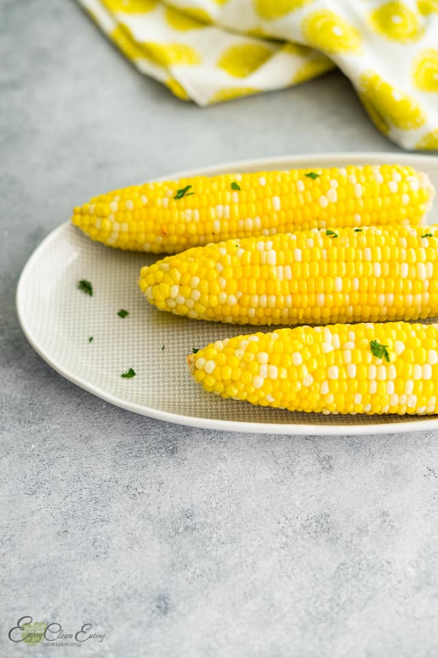 corn serve on oval plate with sprinkle of green herbs