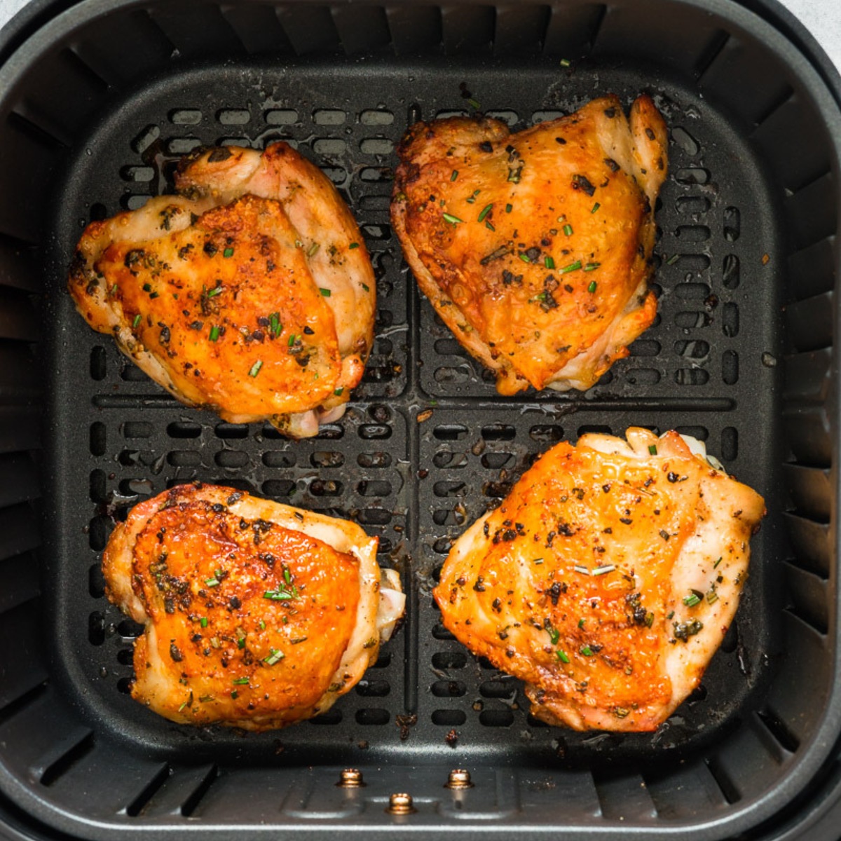 air fryer chicken thighs in the basket.