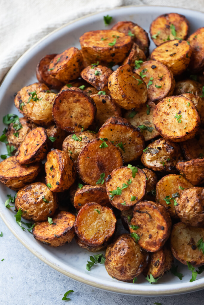 Roasted small potatoes in air fryer, serve as a side dish garnish with chopped parsley.