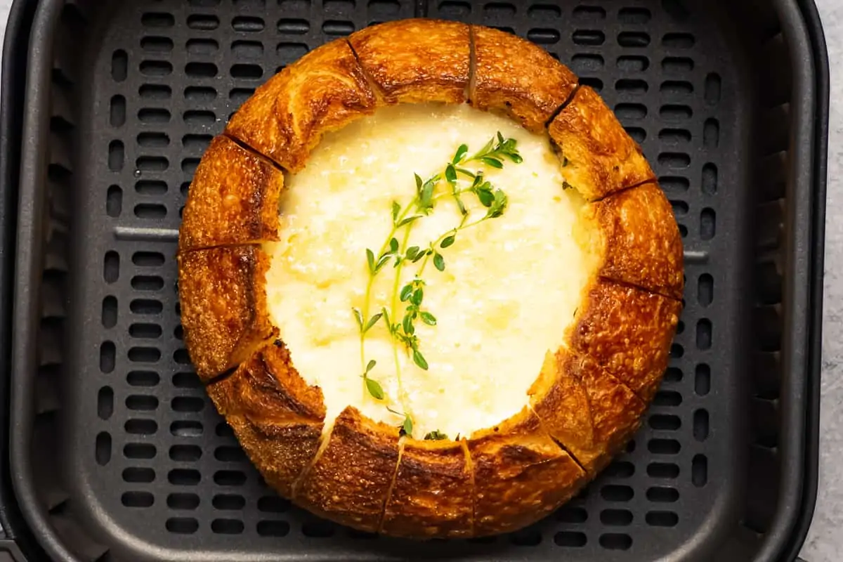 Perfectly crispy bread bowl stuffed with brie cheese in the air fryer basket.