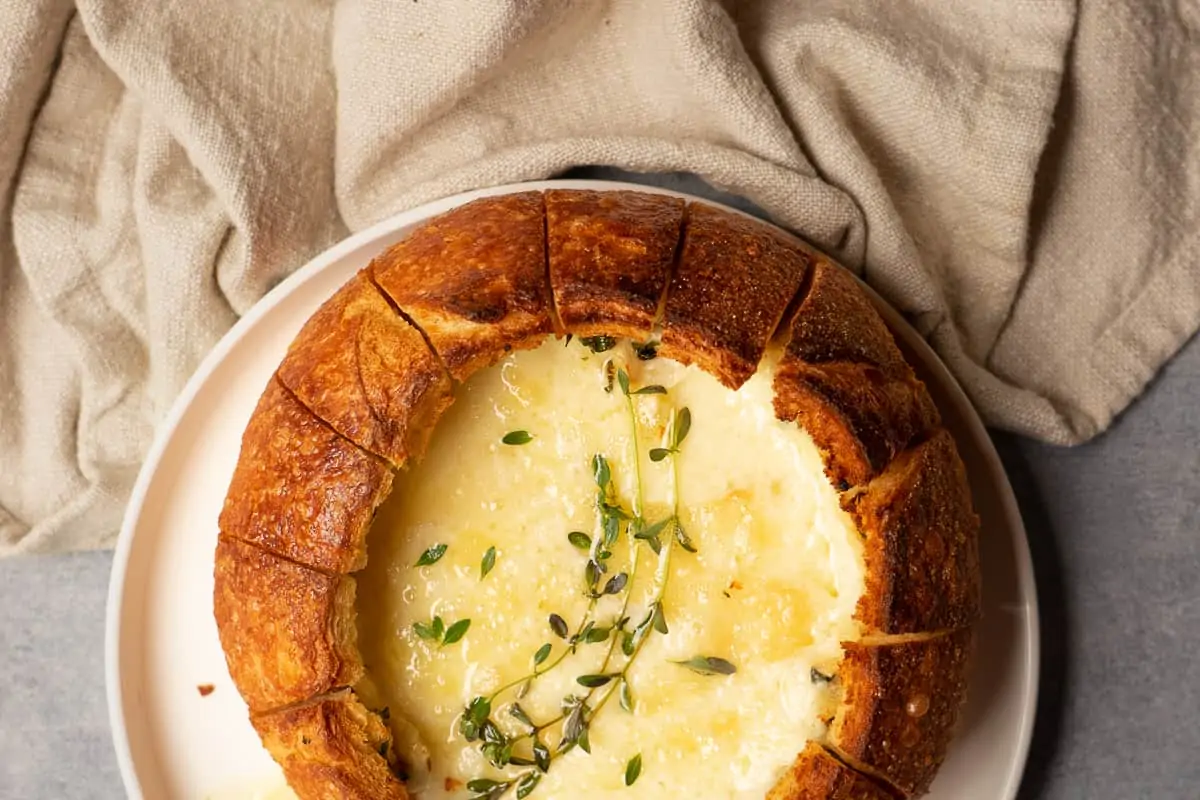 Baked brie cheese in a bread bowl .