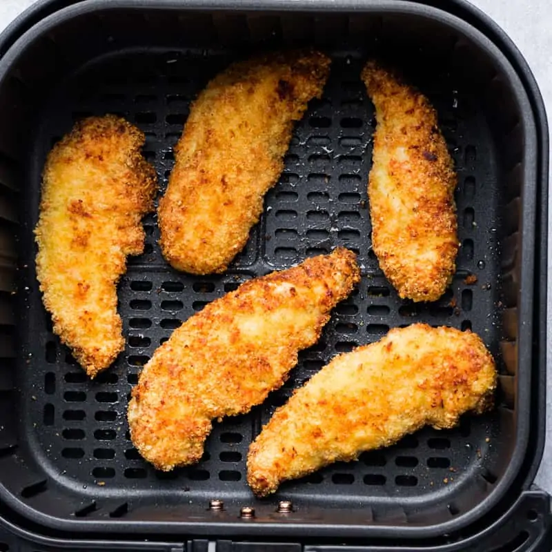 Air fryer breaded chicken tenders in the basket after cooking.