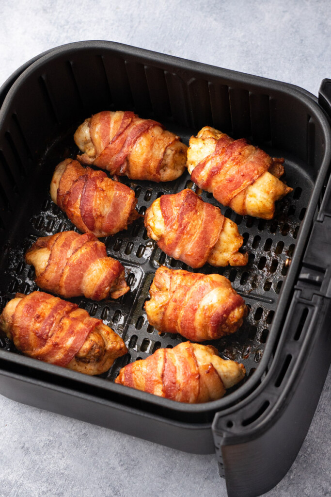 After air frying, the bacon wrapped chicken thighs inside the basket.