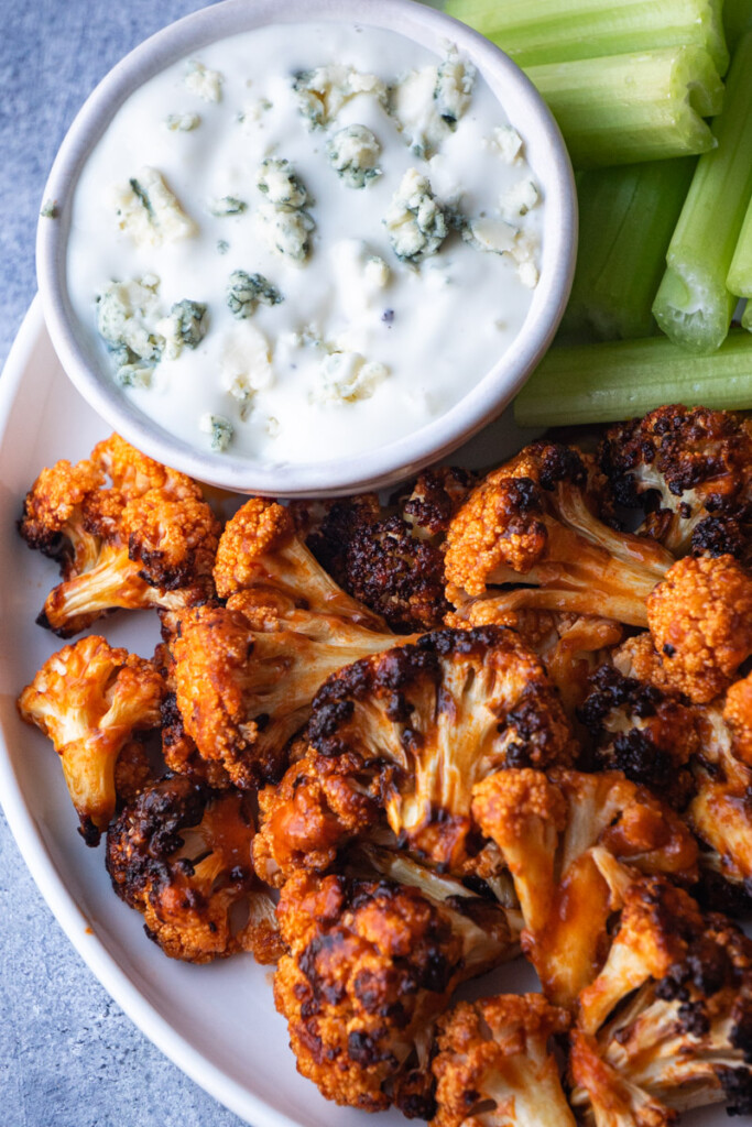Buffalo cauliflower air fryer serve with blue cheese ranch and celery sticks.