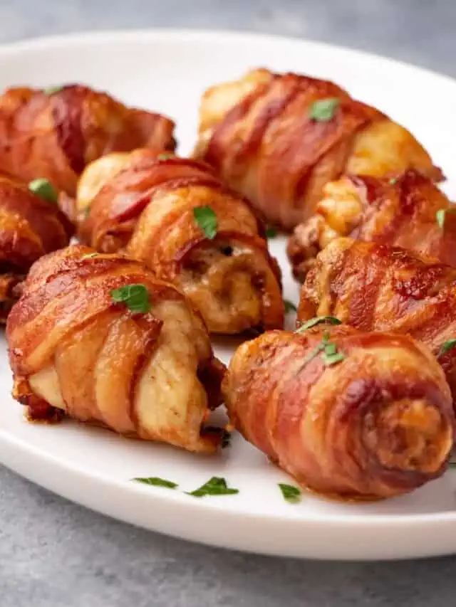 Air fryer bacon-wrapped chicken thighs served on a plate and garnished with fresh herbs.
