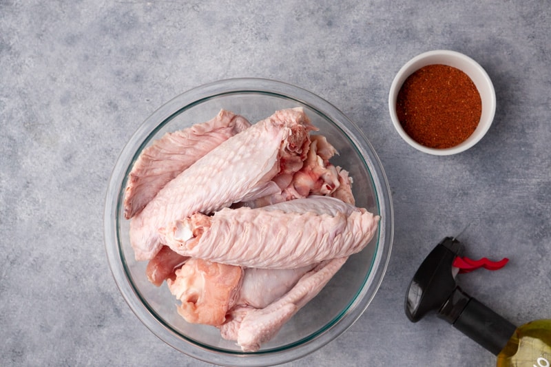ingredients: turkey wings in a bowl, seasoning in a small bowl and sprayer bottle with oil.