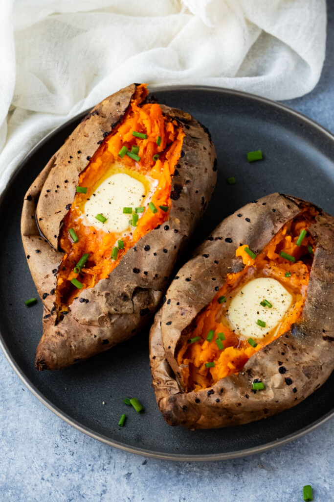 Whole baked sweet potatoes sprinkle with chives and top with butter.