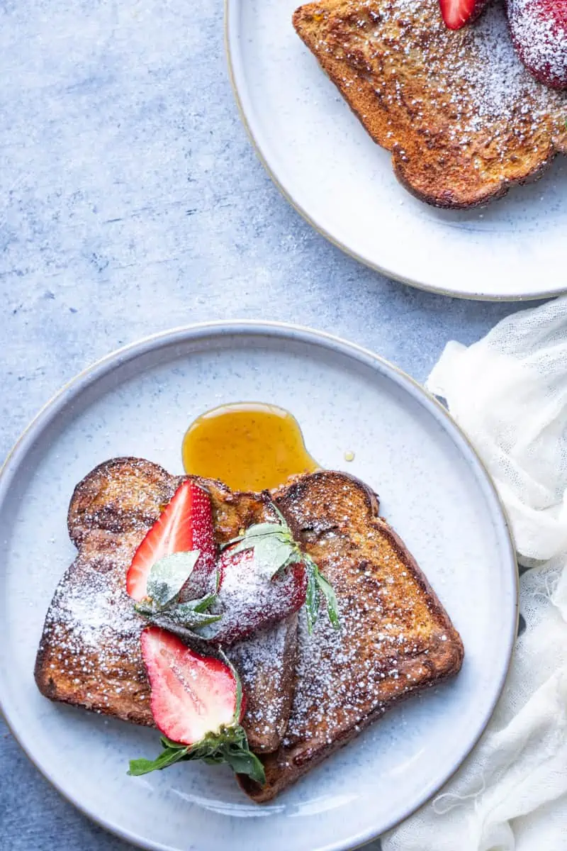 Air fryer french toast with fresh fruits, powder sugar, and maple syrup.