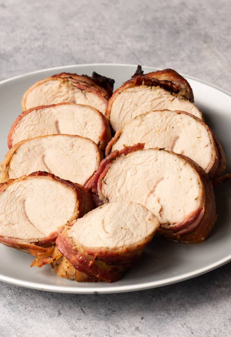 bacon wrapped turkey tenderloin sliced on a plater.