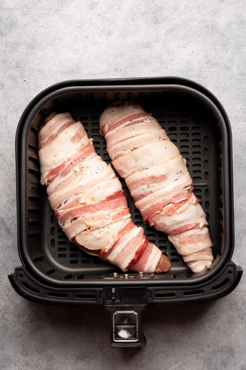 bacon wrapped turkey tenderloins inside the air fryer basket.