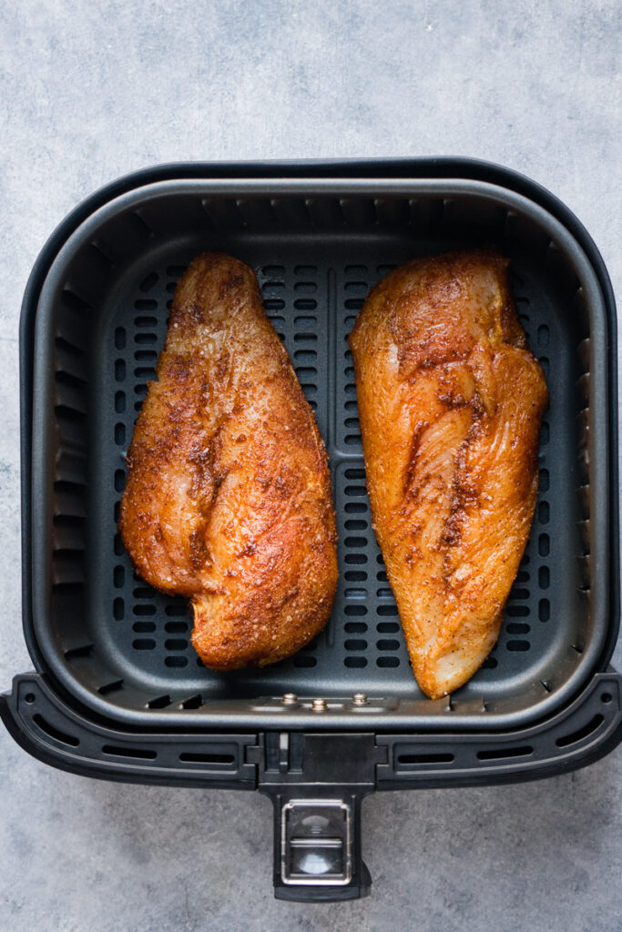 Chicken breasts inside the air fryer before cooking.