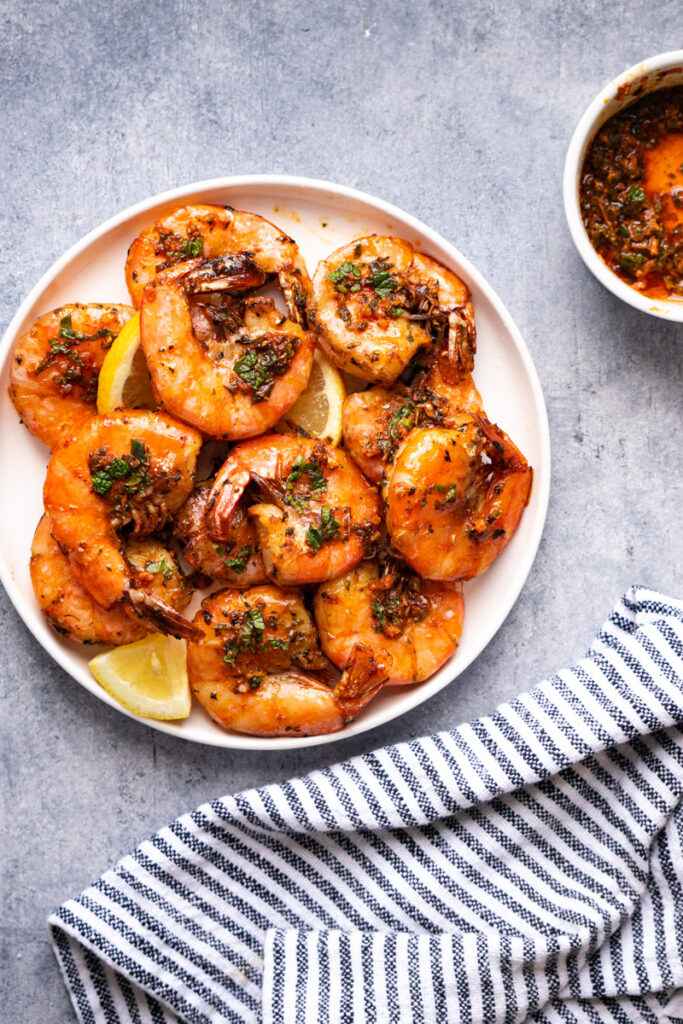 Large shrimp air fryer recipe serves on a plate with lemon and sauce on the side for dipping.