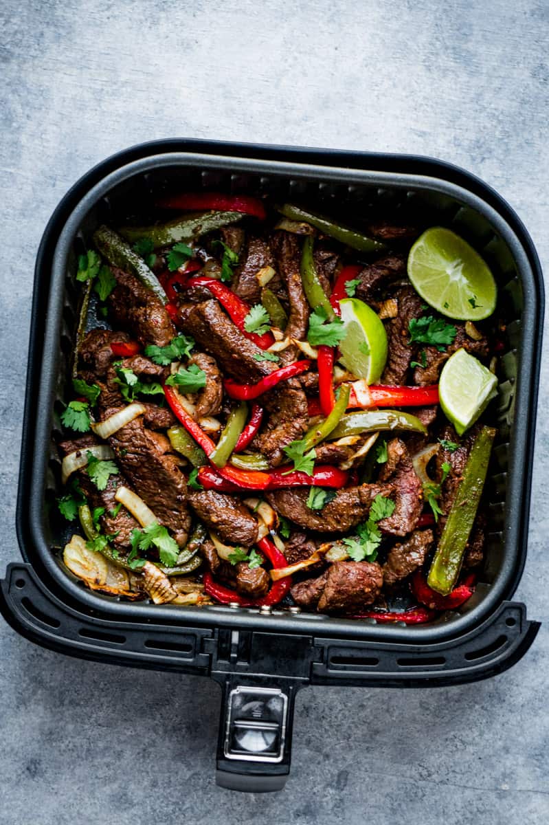 steak fajitas in the air fryer basket and top with lime wedges and chopped fresh cilantro