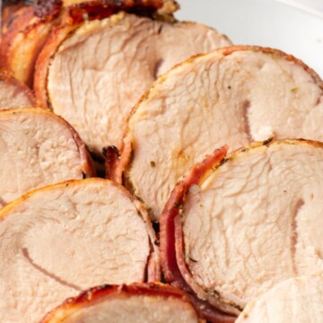 air fryer bacon wrapped turkey tenderloin sliced on a plate.