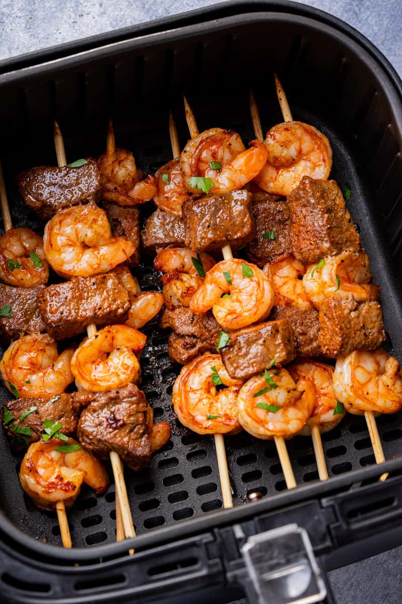 Steak and Shrimp kabobs in air fryer basket sprinkle with fresh cilantro.