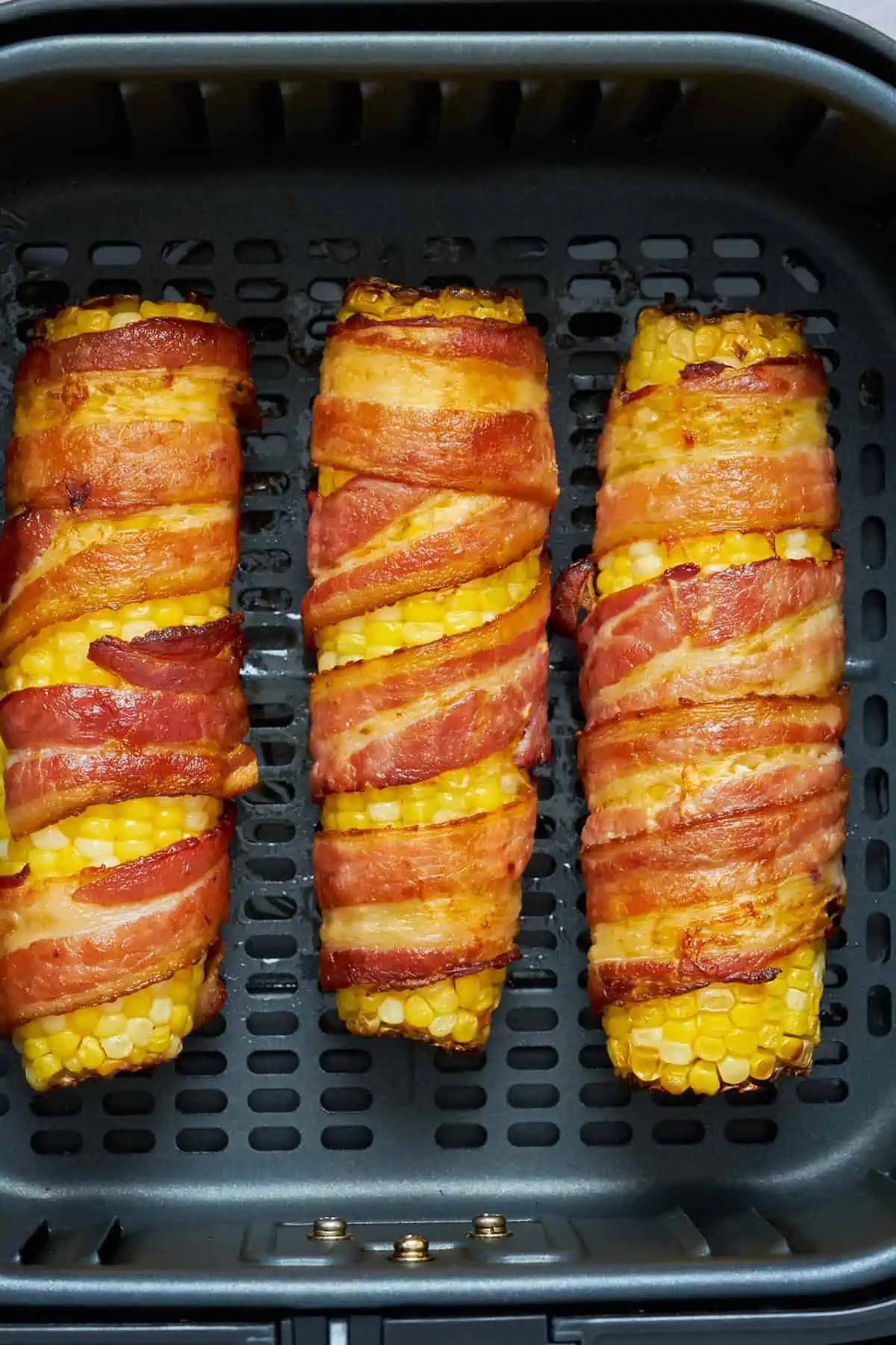 air fryer bacon wrapped corn on the cob in the basket. 