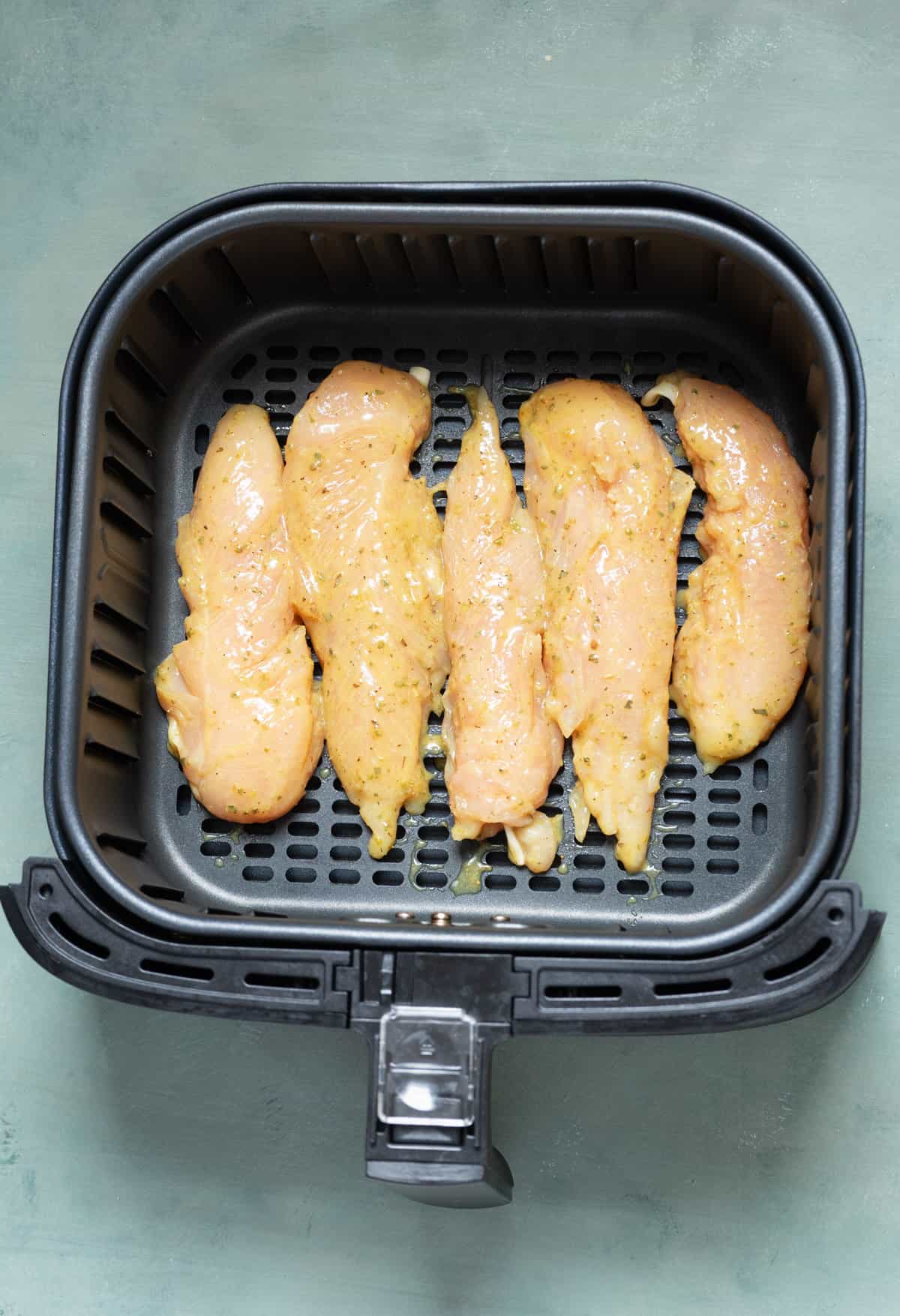 Uncooked chicken tenderloins in the air fryer.