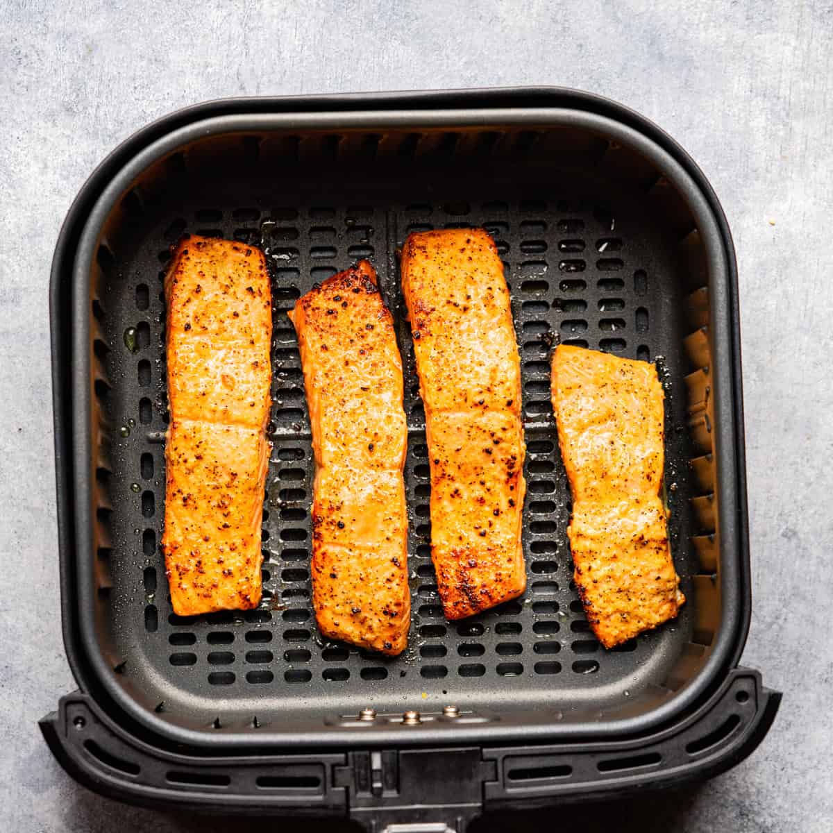 Air fried salmon in the air fryer basket.