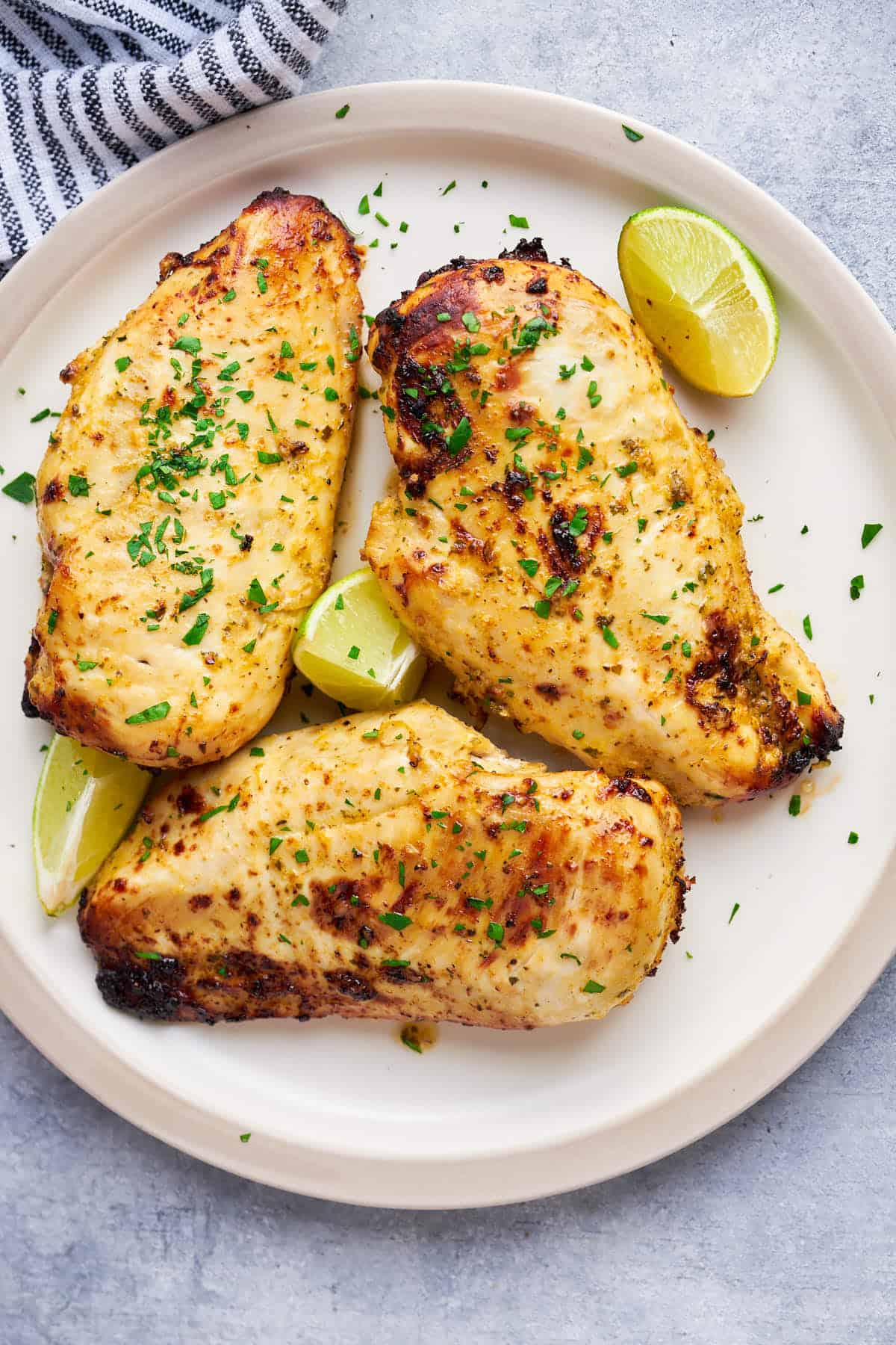 Marinated Chicken breasts plated with lemon and fresh chopped parsley.