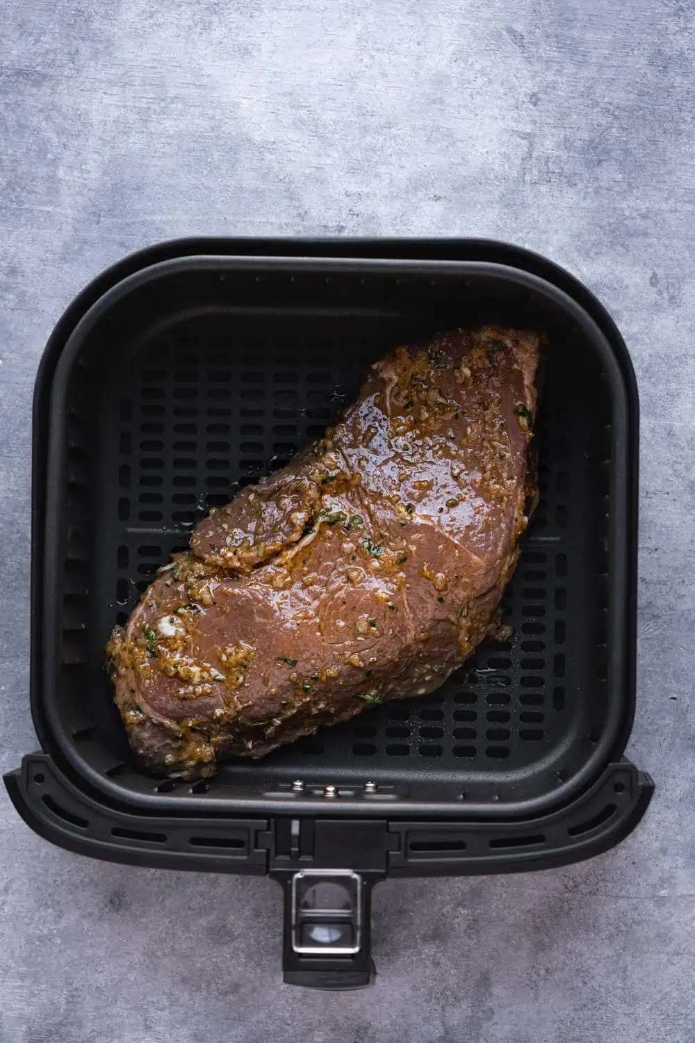 Uncooked marinated steak in the air fryer.
