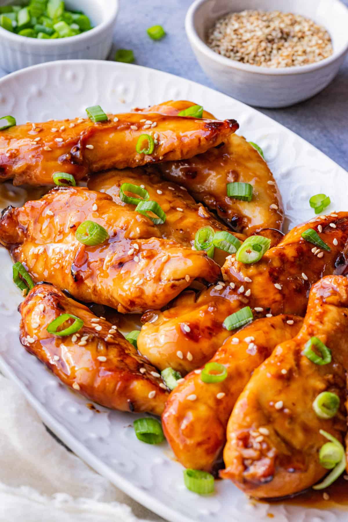 Teriyaki chicken tenders in air fryer garnished with sesame seed and fresh green onions.