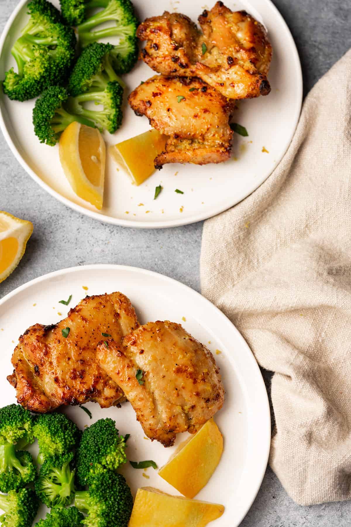 Lemon pepper chicken thighs served with broccoli and lemon.