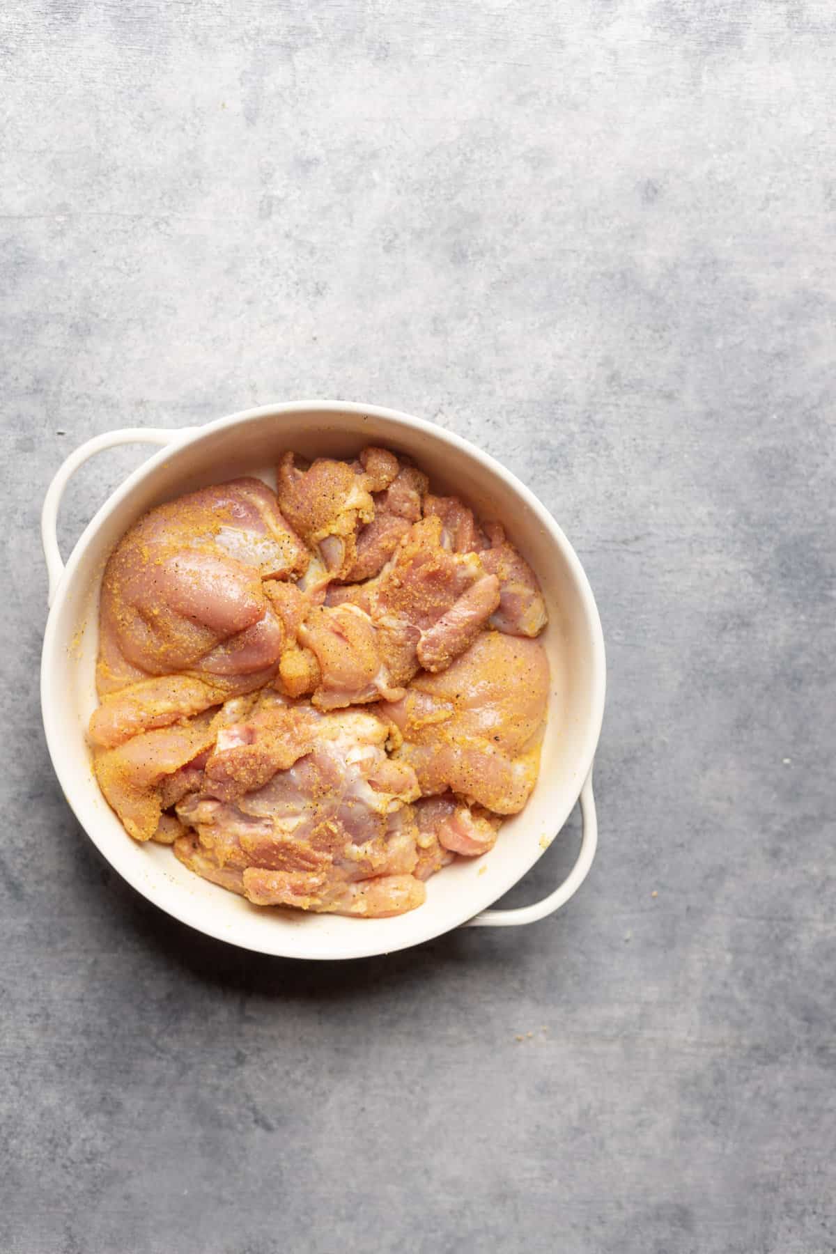Coated chicken thighs in a large bowl.