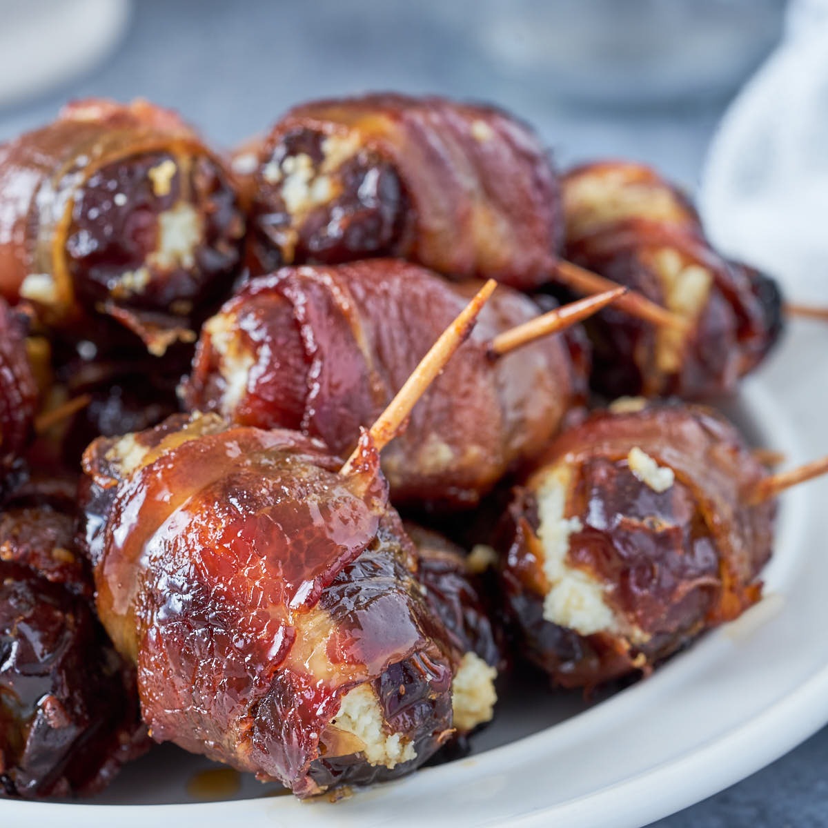 Air fryer bacon wrapped dates stuffed with goat cheese serve on a plate.