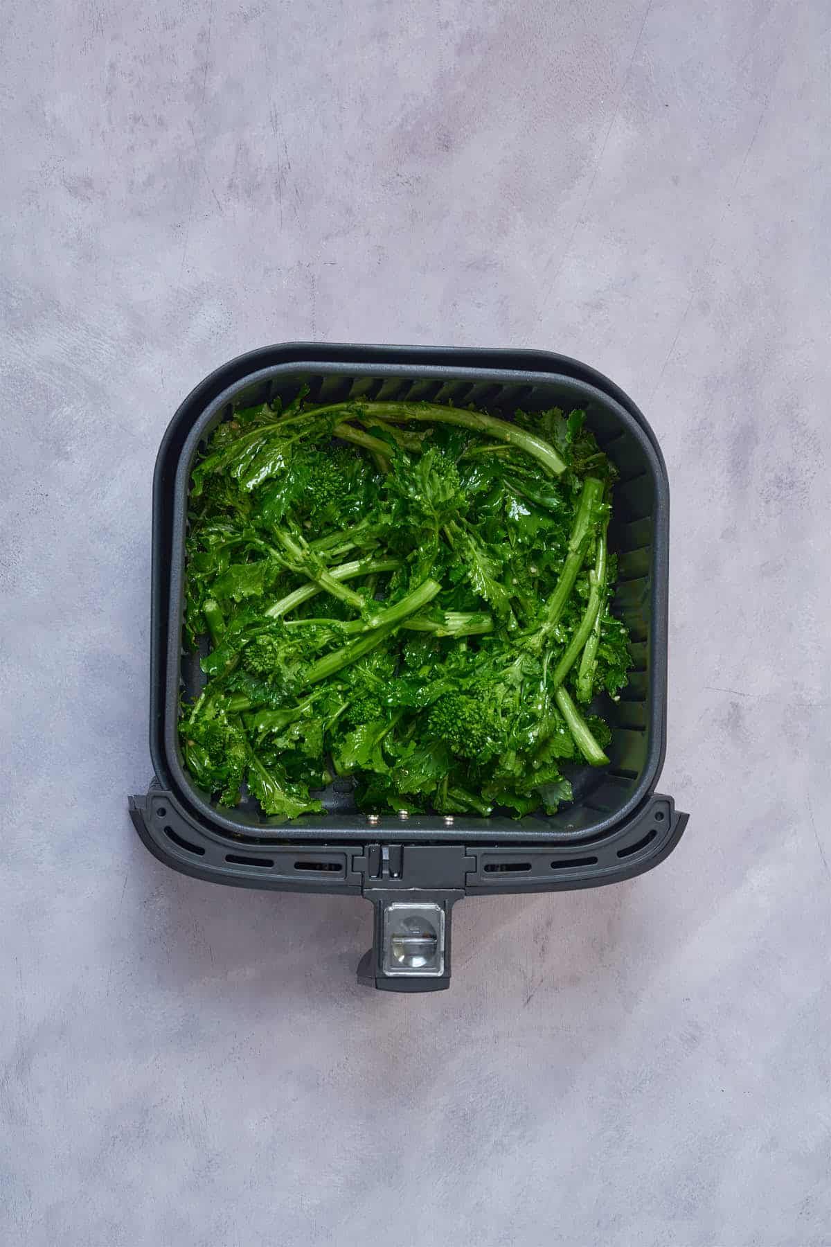 Broccoli rabe in the air fryer basket before cooking.