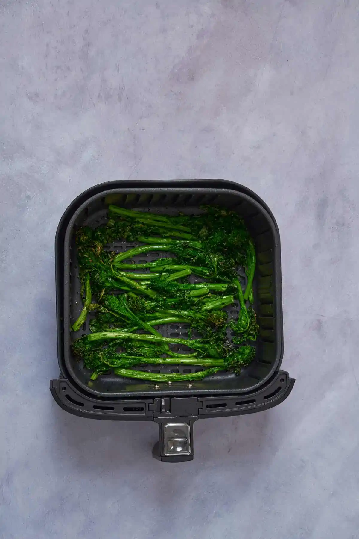 Air fried broccoli rabe in the air fryer basket.