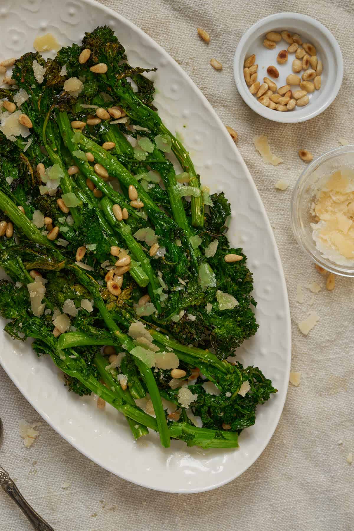Broccoli rabe in air fryer served with cheese, lemon, and toasted pine nuts.