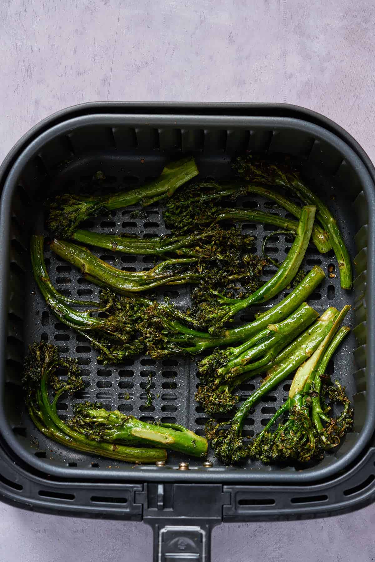 Air fried broccolini in the air fryer basket.